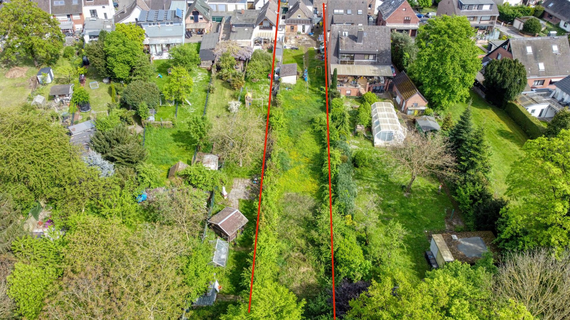 Luftaufnahme eines langen, schmalen Gartengrundstücks mit roter Markierung, umgeben von Bäumen und Nachbarhäusern.