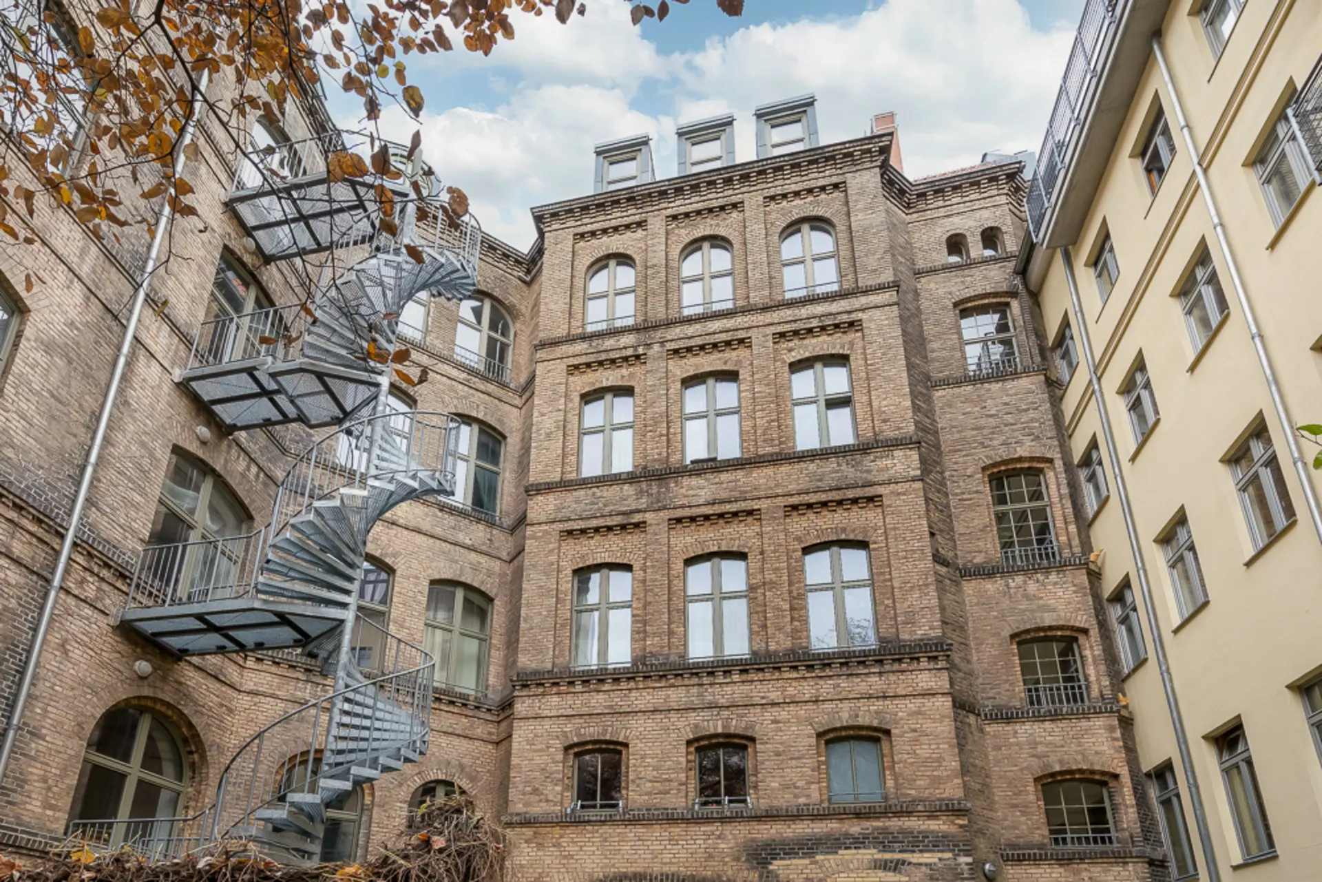 Backstein-Wohngebäude mit Außentreppe und mehreren Fenstern im Innenhof.