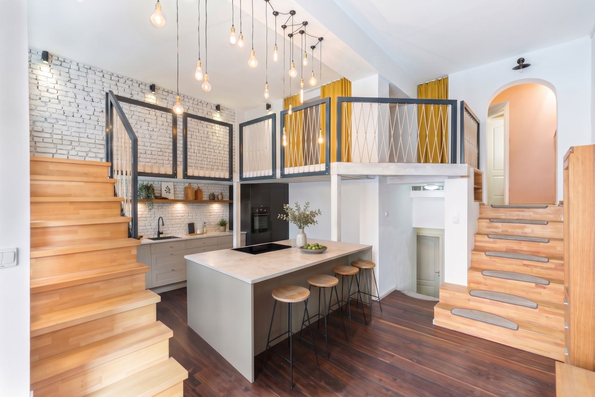 Moderne offene Küche mit Insel, Holztreppen zu zwei offenen Galerien und vielen Hängelampen.