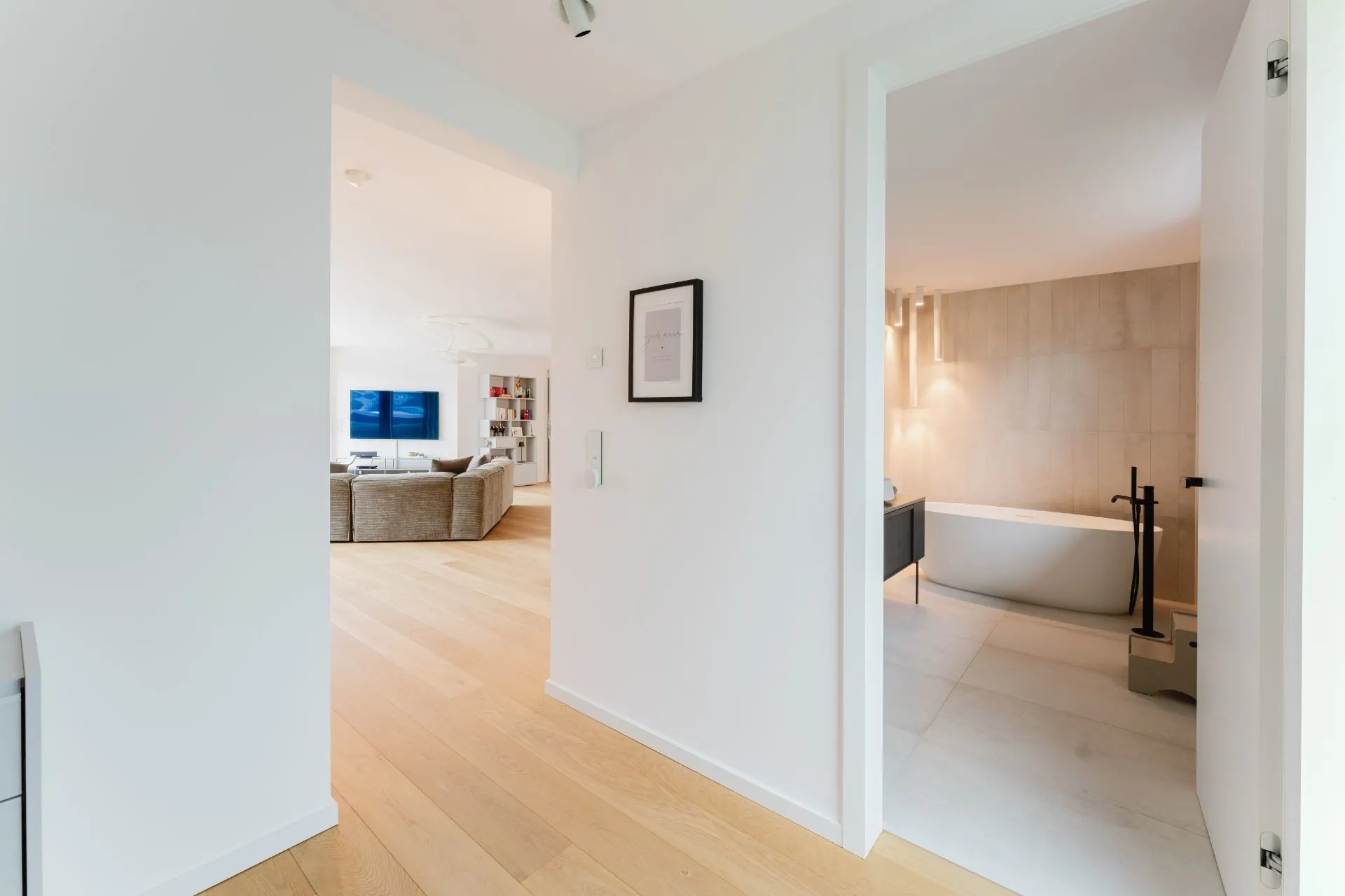 Heller Flur mit Blick ins Wohnzimmer und ins Badezimmer mit freistehender Badewanne.