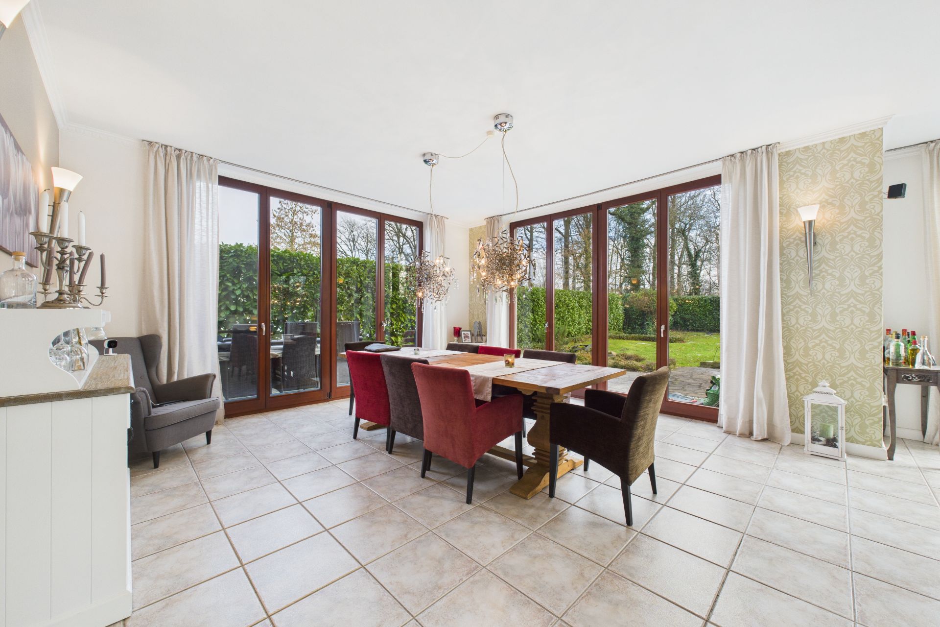 Helles Esszimmer mit großem Holztisch, sechs Stühlen und Blick auf den Garten durch Glasfronten.