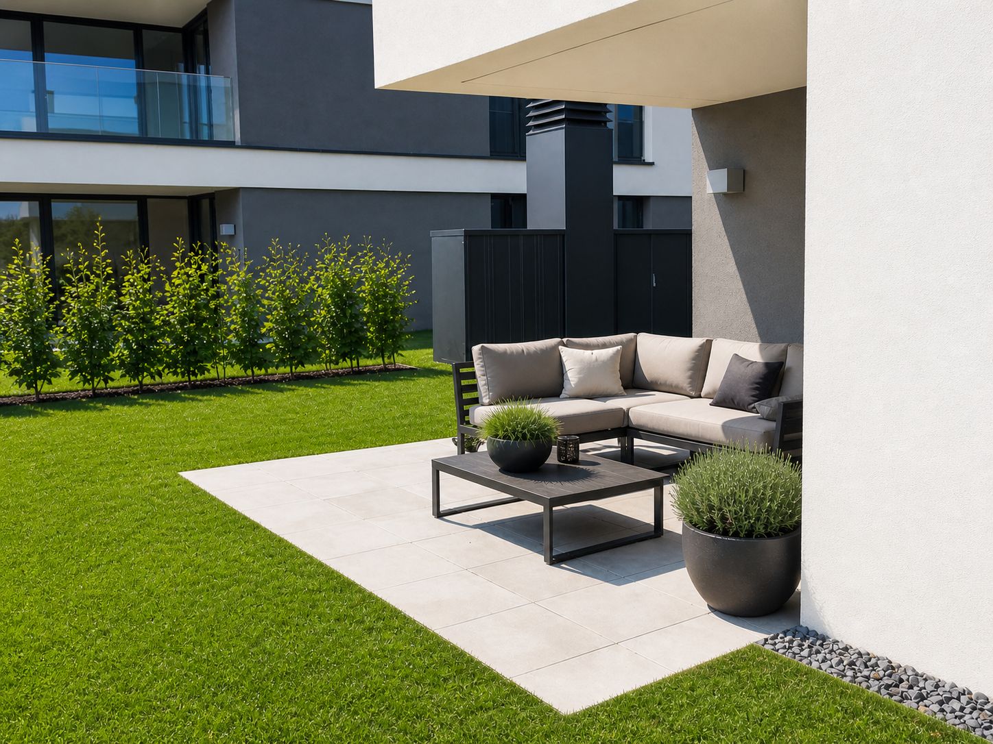 Moderne Terrasse mit Ecksofa, Tisch und zwei Pflanzkübeln auf Fliesen, umgeben von Rasen.