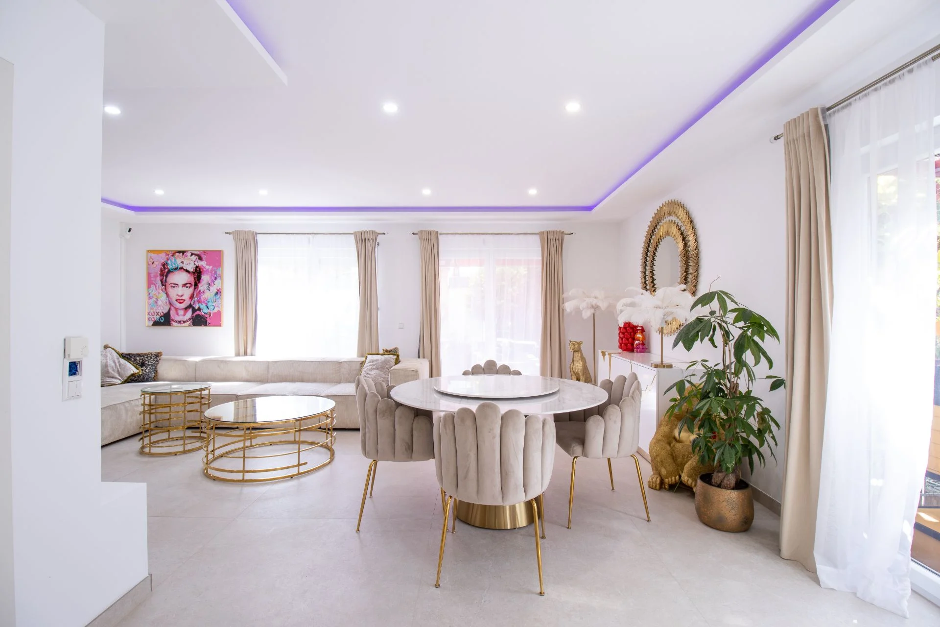 Heller Wohn- und Essbereich mit runden Tischen, Stühlen, Sofa, Pflanzen und großen Fenstern.