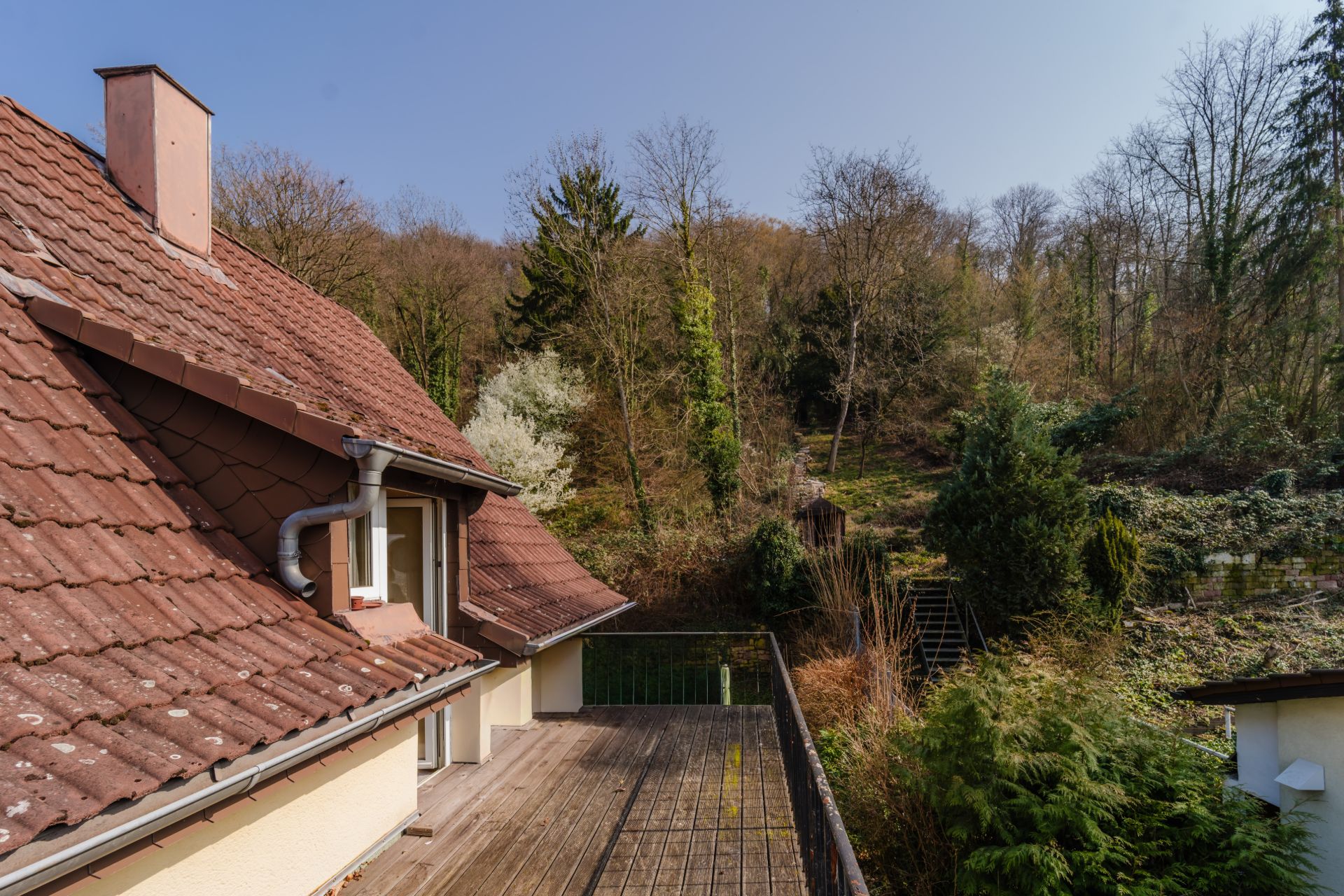 Holzterrasse an einem Wohnhaus mit Blick auf einen bewaldeten Hang.