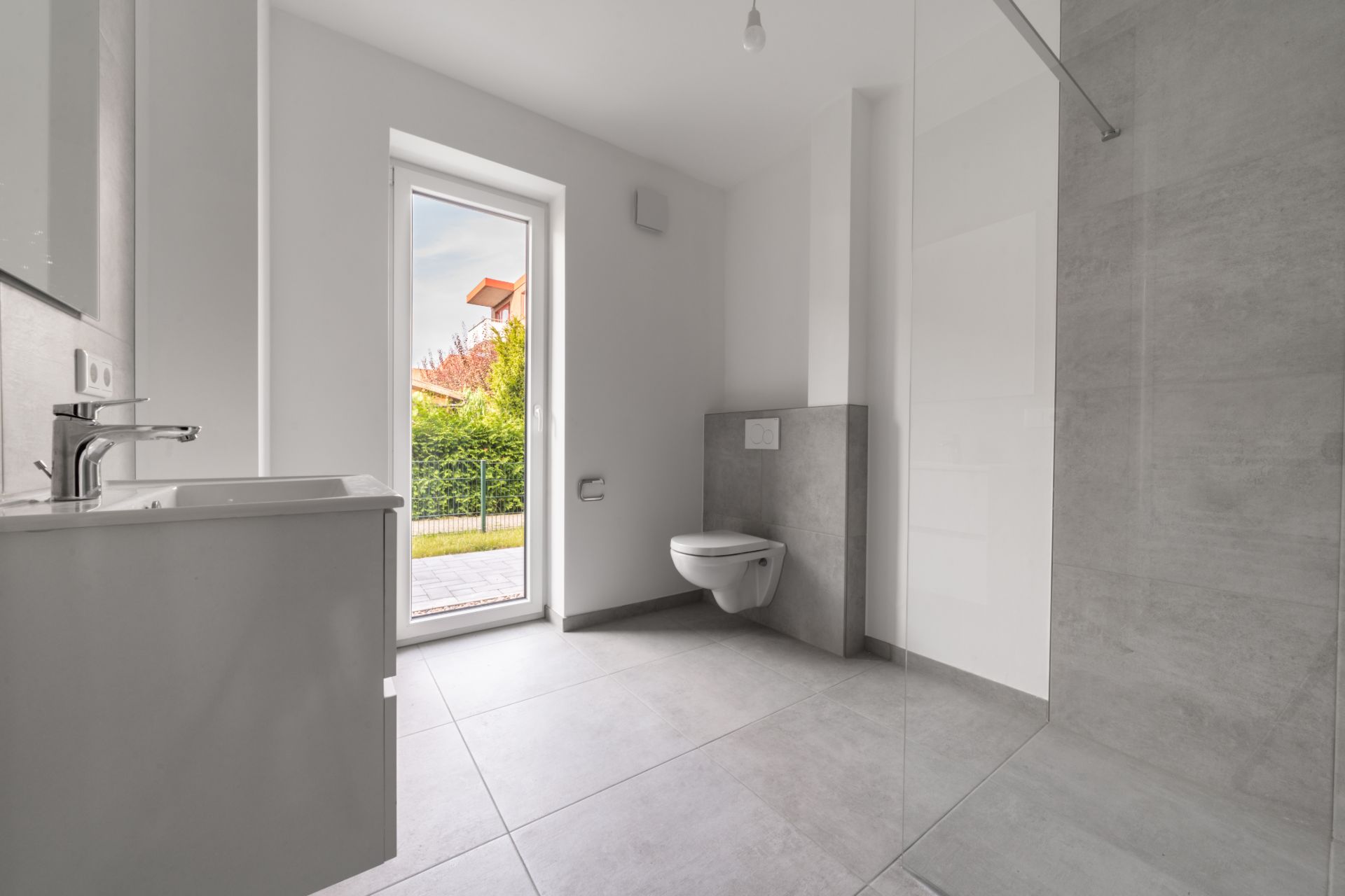 Modernes Badezimmer mit bodentiefem Fenster, Toilette, Waschbecken und begehbarer Dusche.