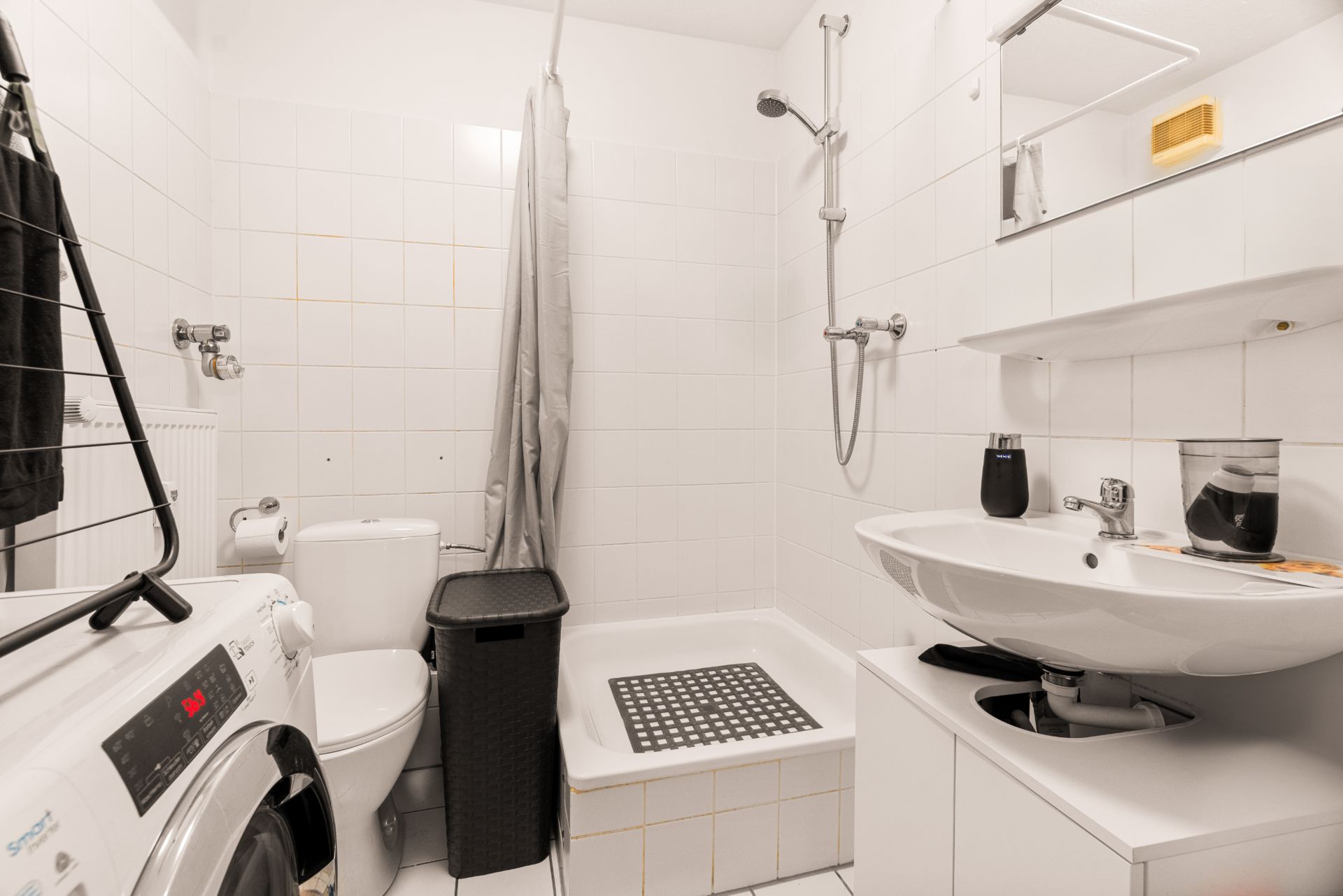 Modernes Badezimmer mit Dusche, Waschbecken, Waschmaschine und WC.