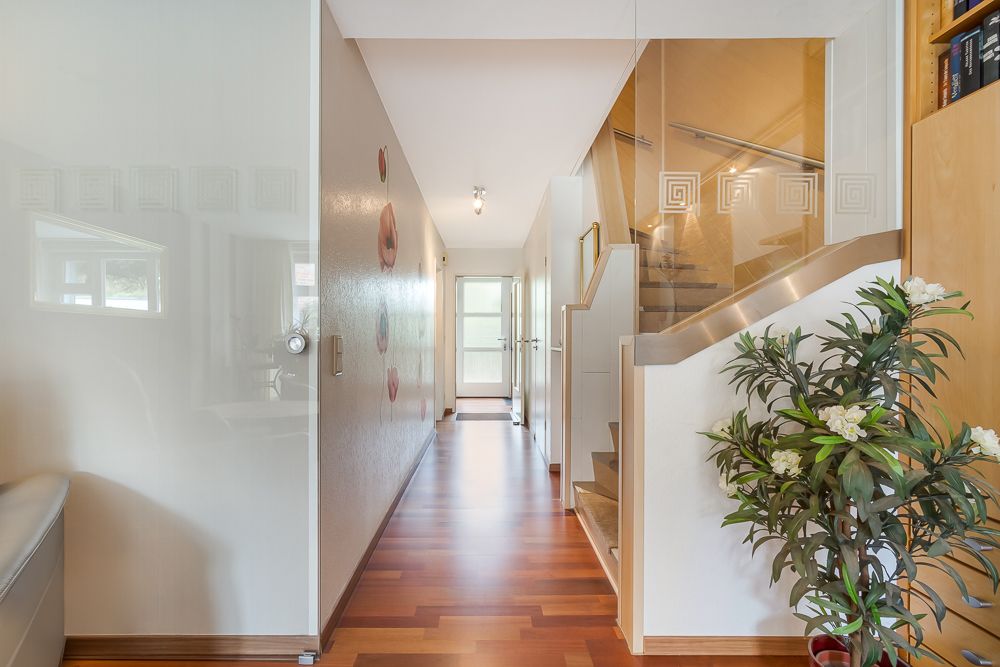 Heller Flur mit Holztreppe, Holzboden, Pflanzen und Wanddeko in einem Wohnhaus.
