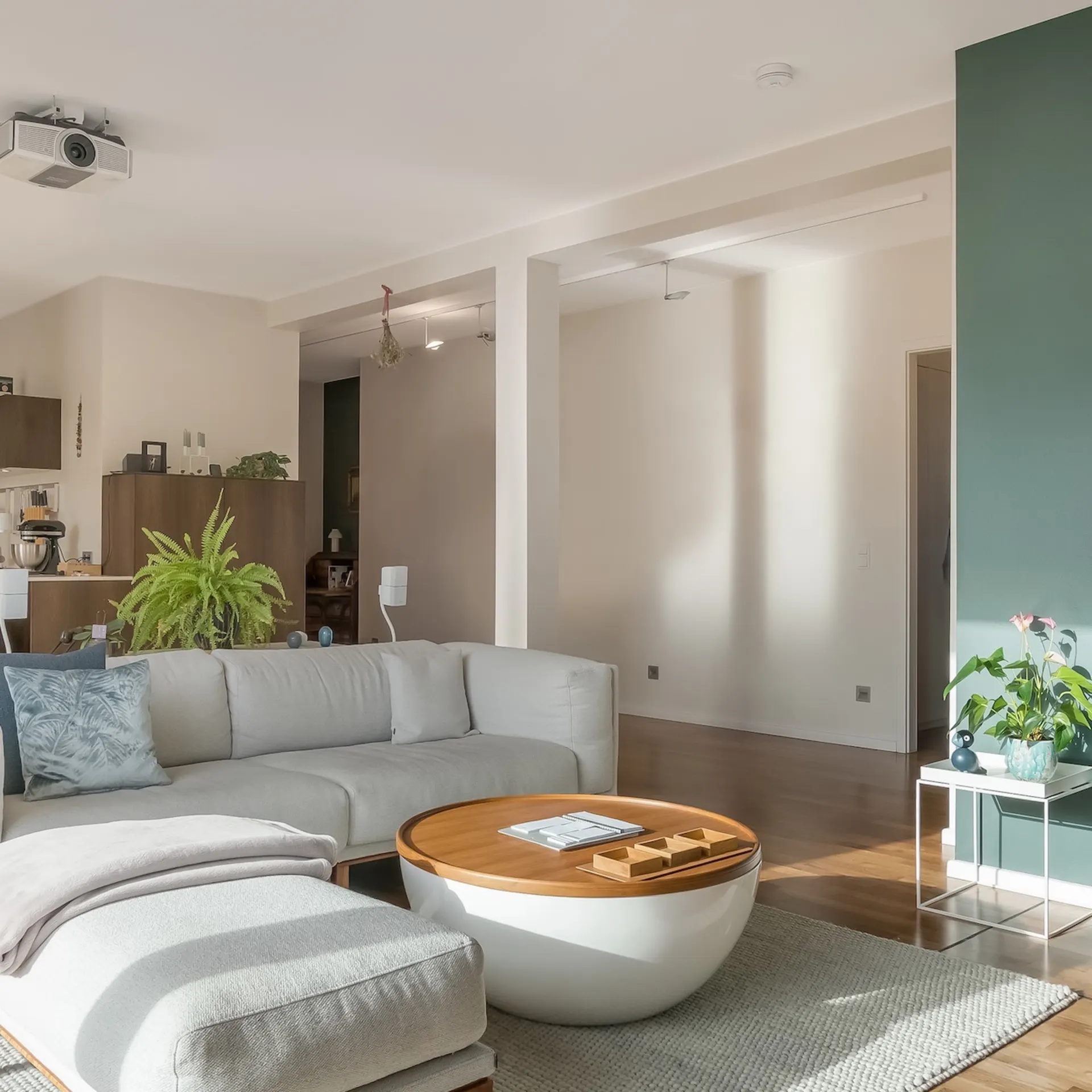 Helles Wohnzimmer mit grauem Sofa, rundem Couchtisch und Pflanzen auf Holzfußboden.