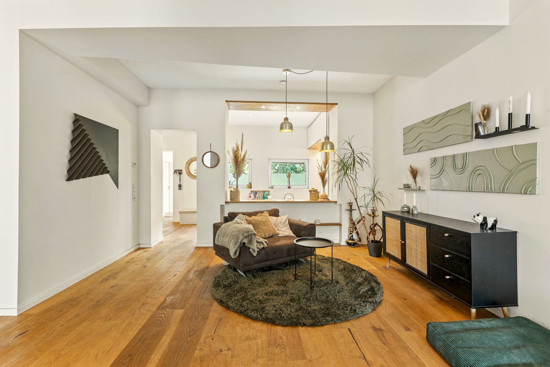 Modernes Wohnzimmer mit Holzfußboden, Sessel, Teppich und Blick in Küche.