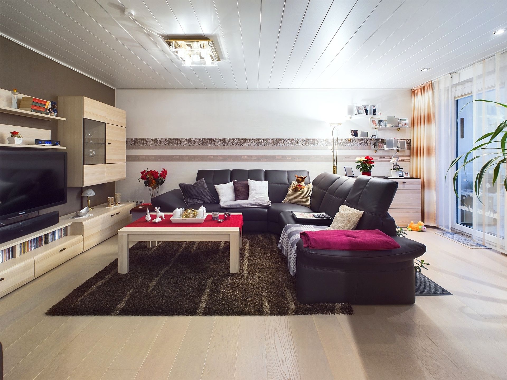 Wohnzimmer mit großer Eckcouch, Couchtisch, Teppich, Fernseher und Regalwand.