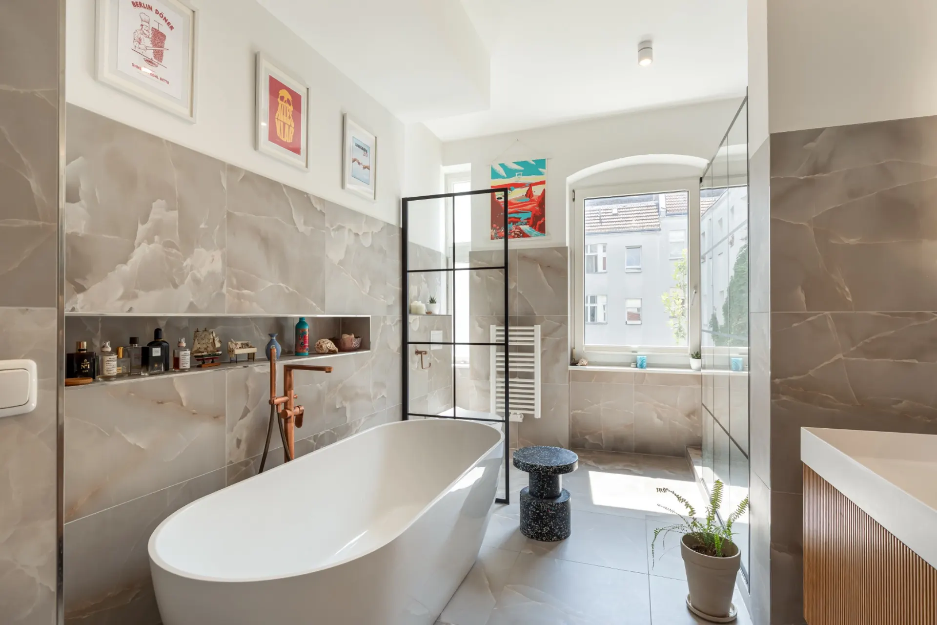 Modernes Badezimmer mit freistehender Badewanne, großem Fenster und Deko-Bildern an der Wand.