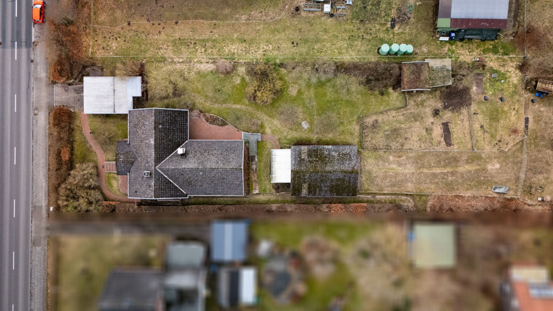 Luftaufnahme eines Hauses mit angrenzendem Garten und Nebengebäuden von oben.