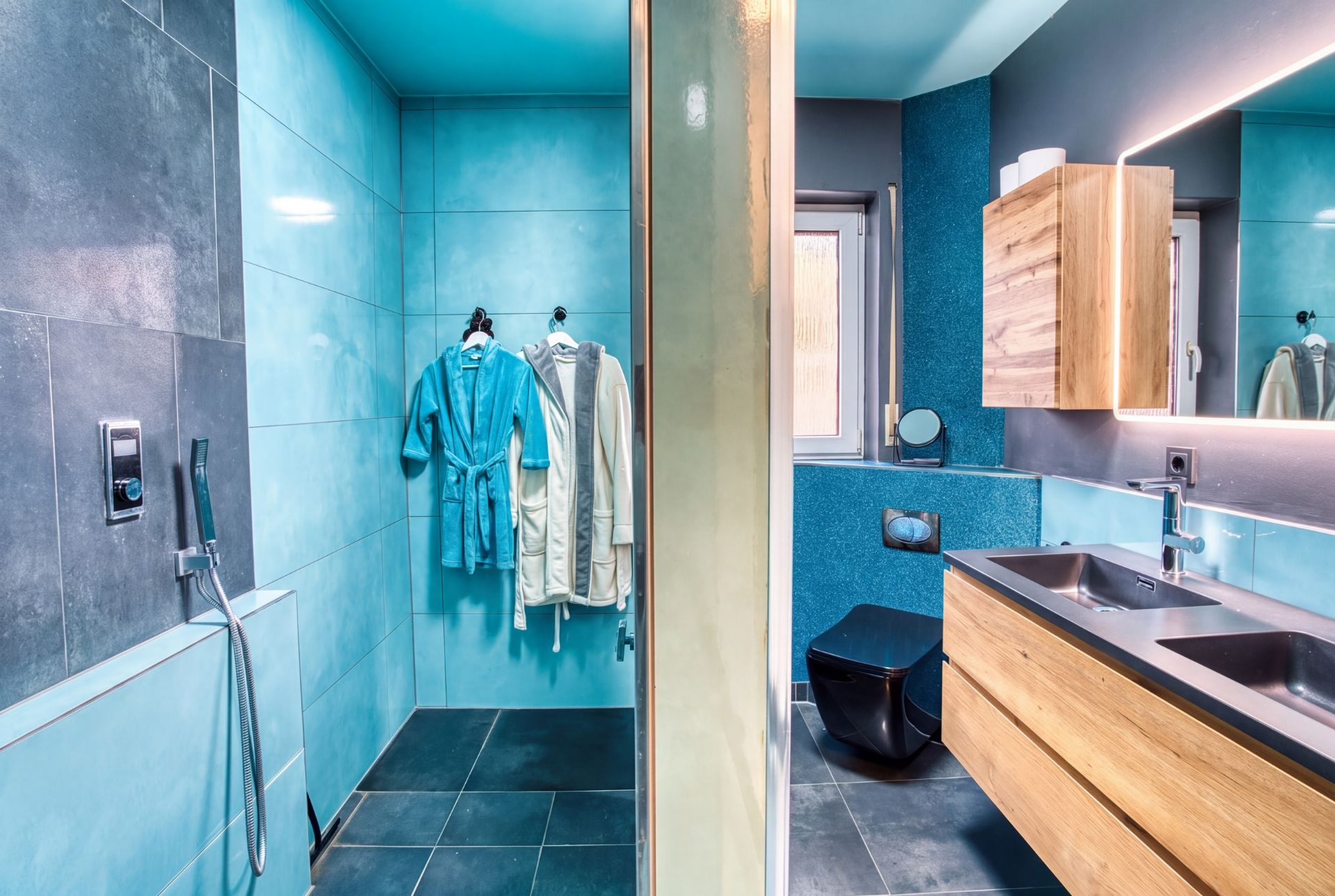 Modernes Badezimmer mit offener Dusche, Doppelwaschbecken, Spiegel und zwei aufgehängten Bademänteln.