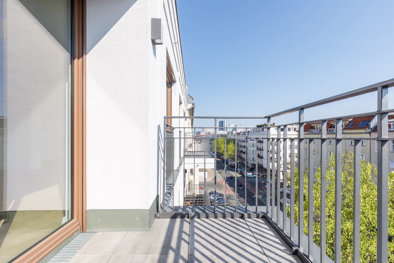 Heller Balkon mit Metallgeländer und Blick auf Straße und Häuser.