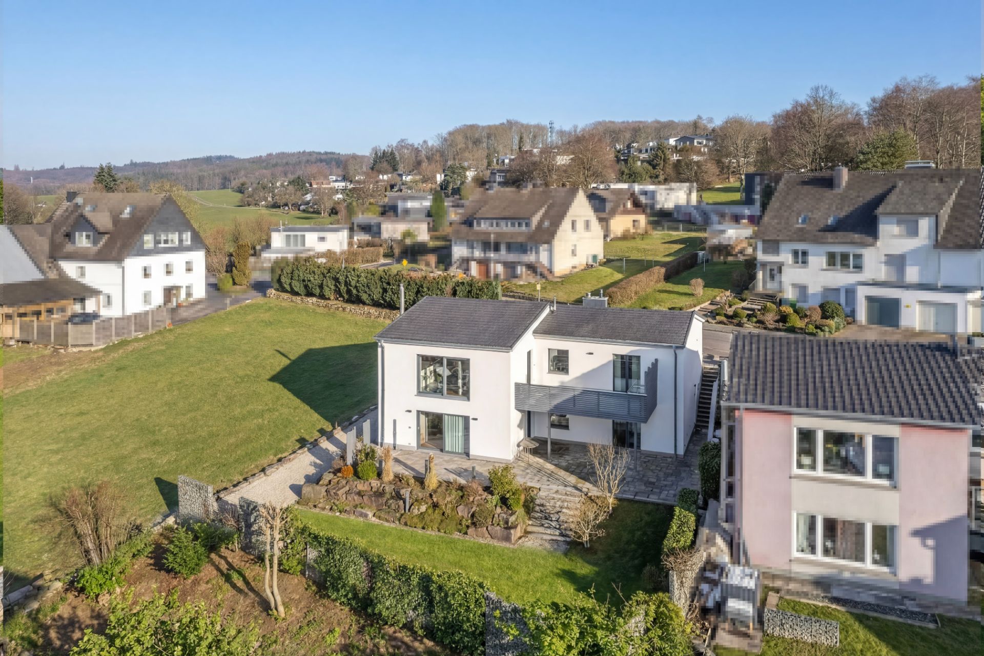 Luftaufnahme eines modernen Hauses mit Garten in einer Wohngegend bei sonnigem Wetter.