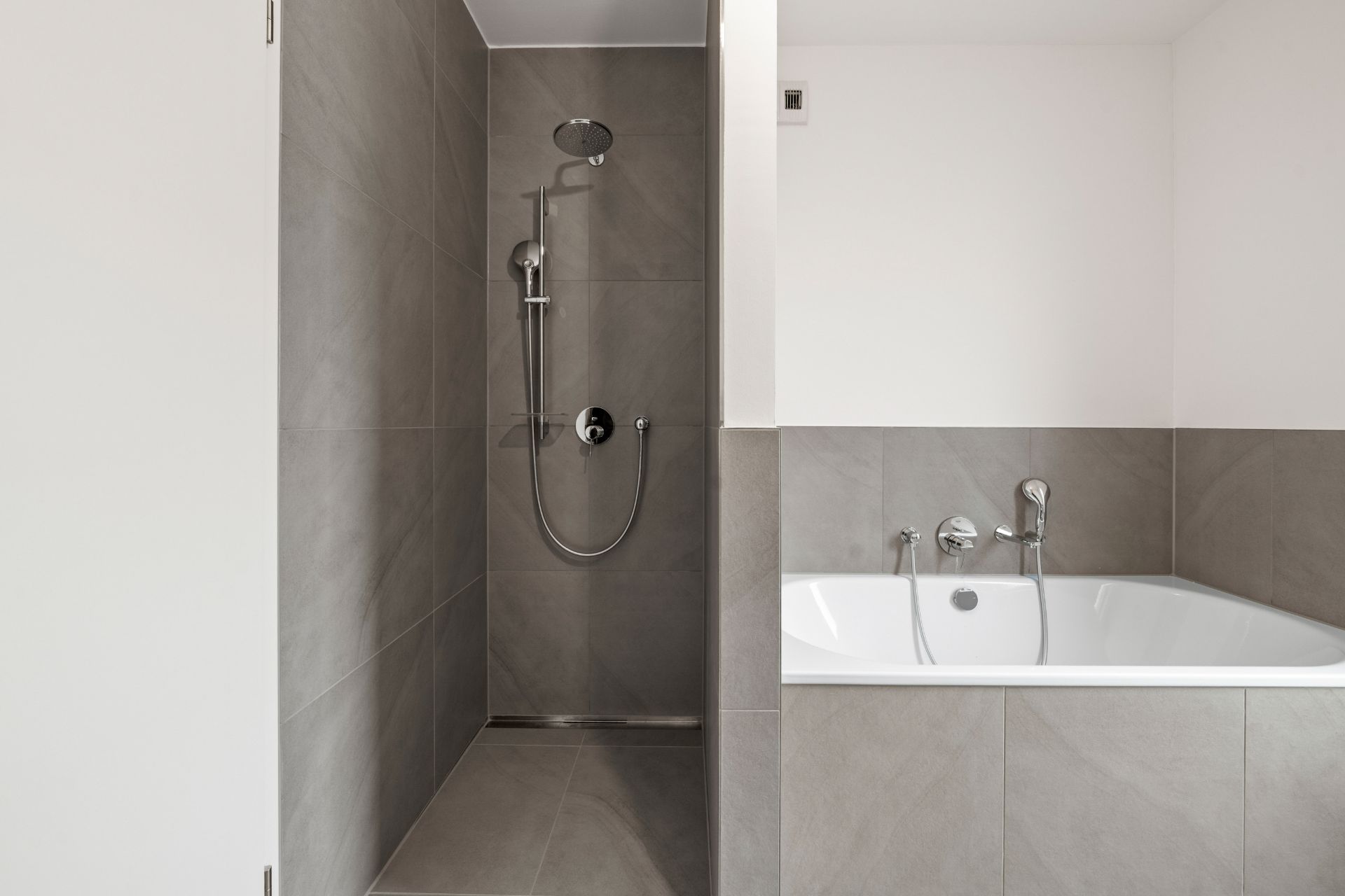 Modernes Bad mit begehbarer Dusche und Badewanne mit grauen Fliesen.