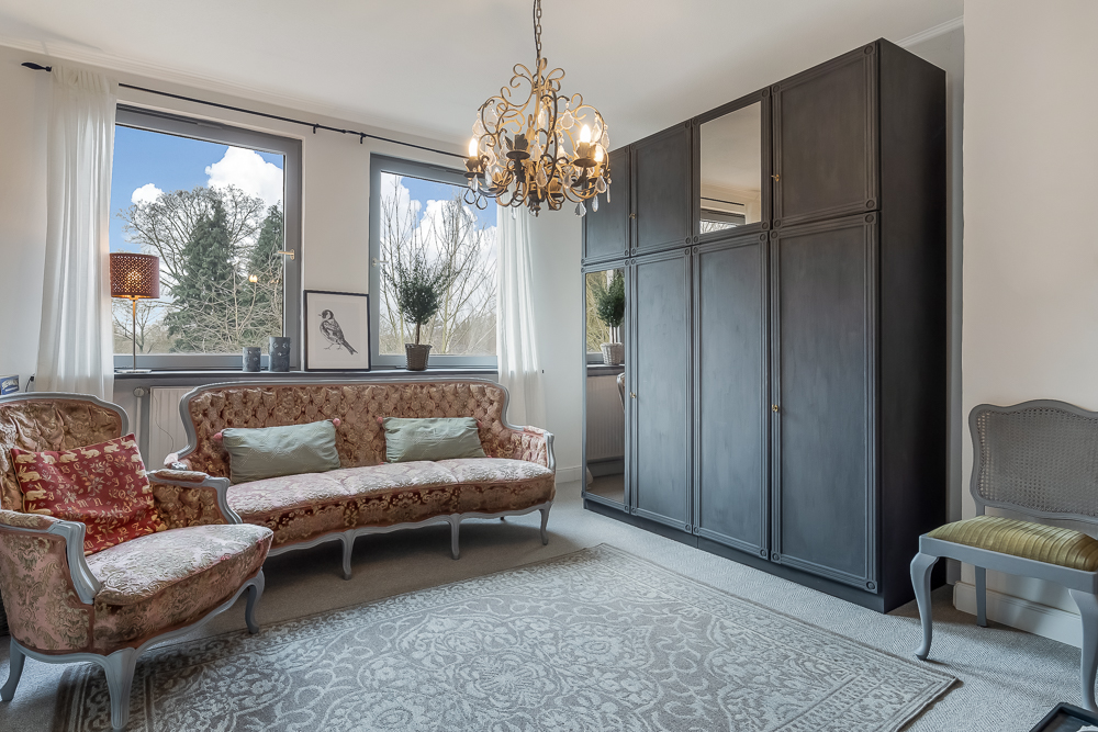 Wohnzimmer mit antiken Möbeln, großem Teppich, schwarzem Schrank und Kronleuchter.