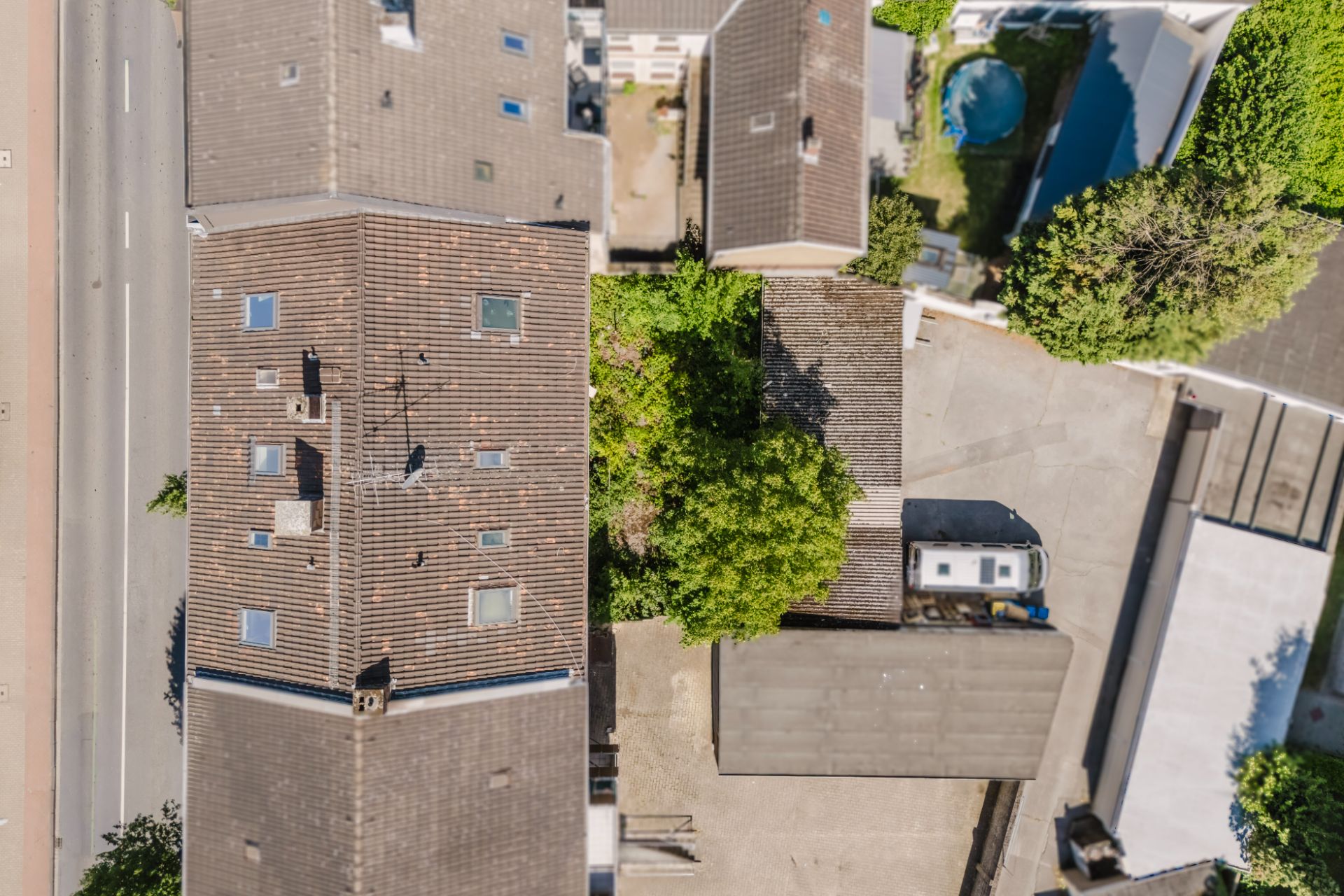 Luftbild von Wohngebäuden, einem Innenhof, Bäumen und einem geparkten Wohnwagen.
