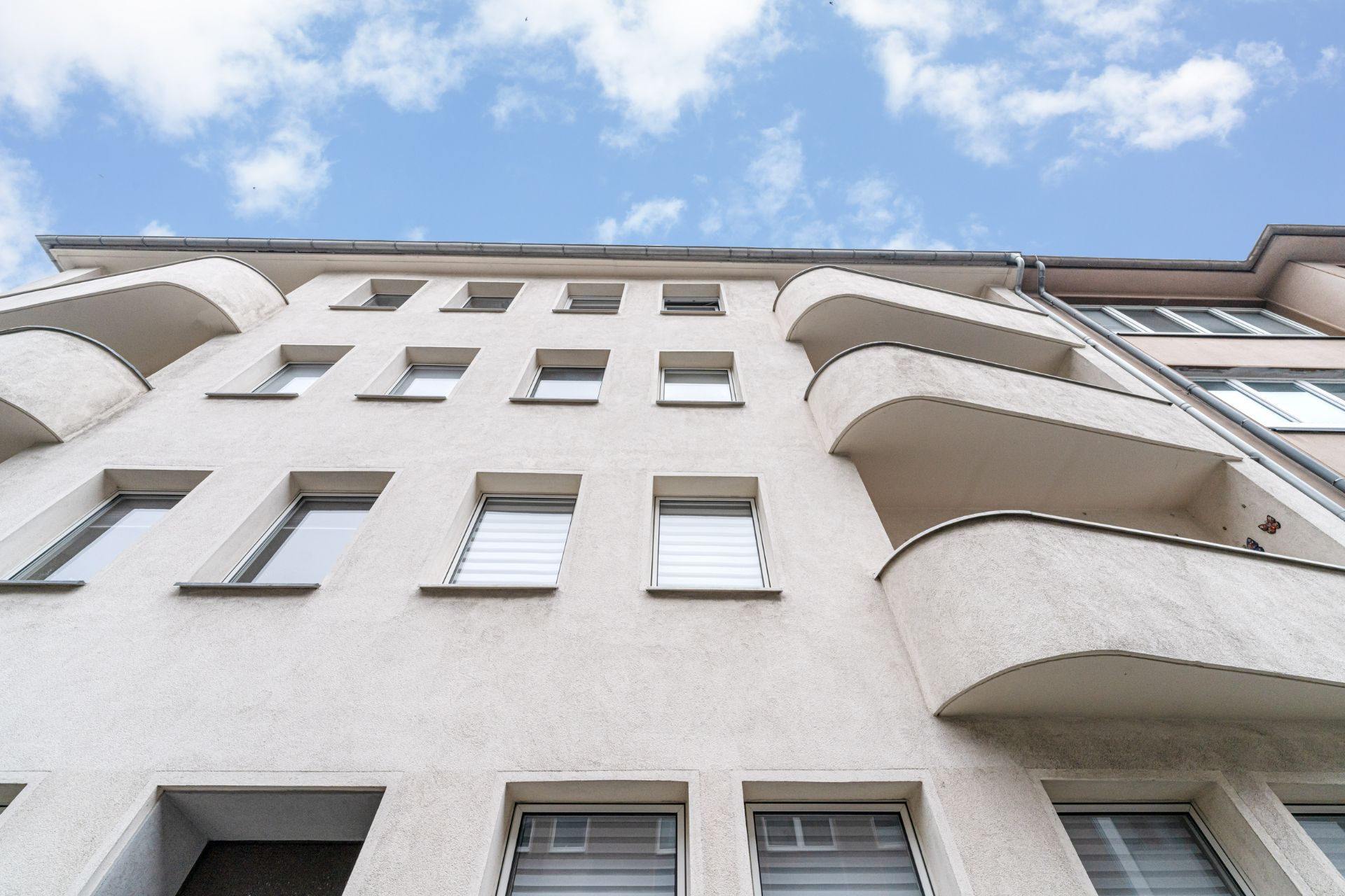 Mehrstöckiges Wohnhaus mit Balkonen und vielen Fenstern, Blick von unten gegen den Himmel.