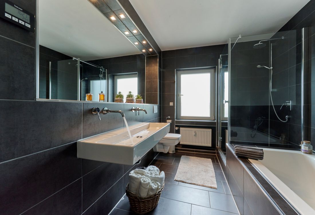 Modernes Badezimmer mit großem Spiegel, Doppelwaschbecken, Dusche, Badewanne und Fenster.