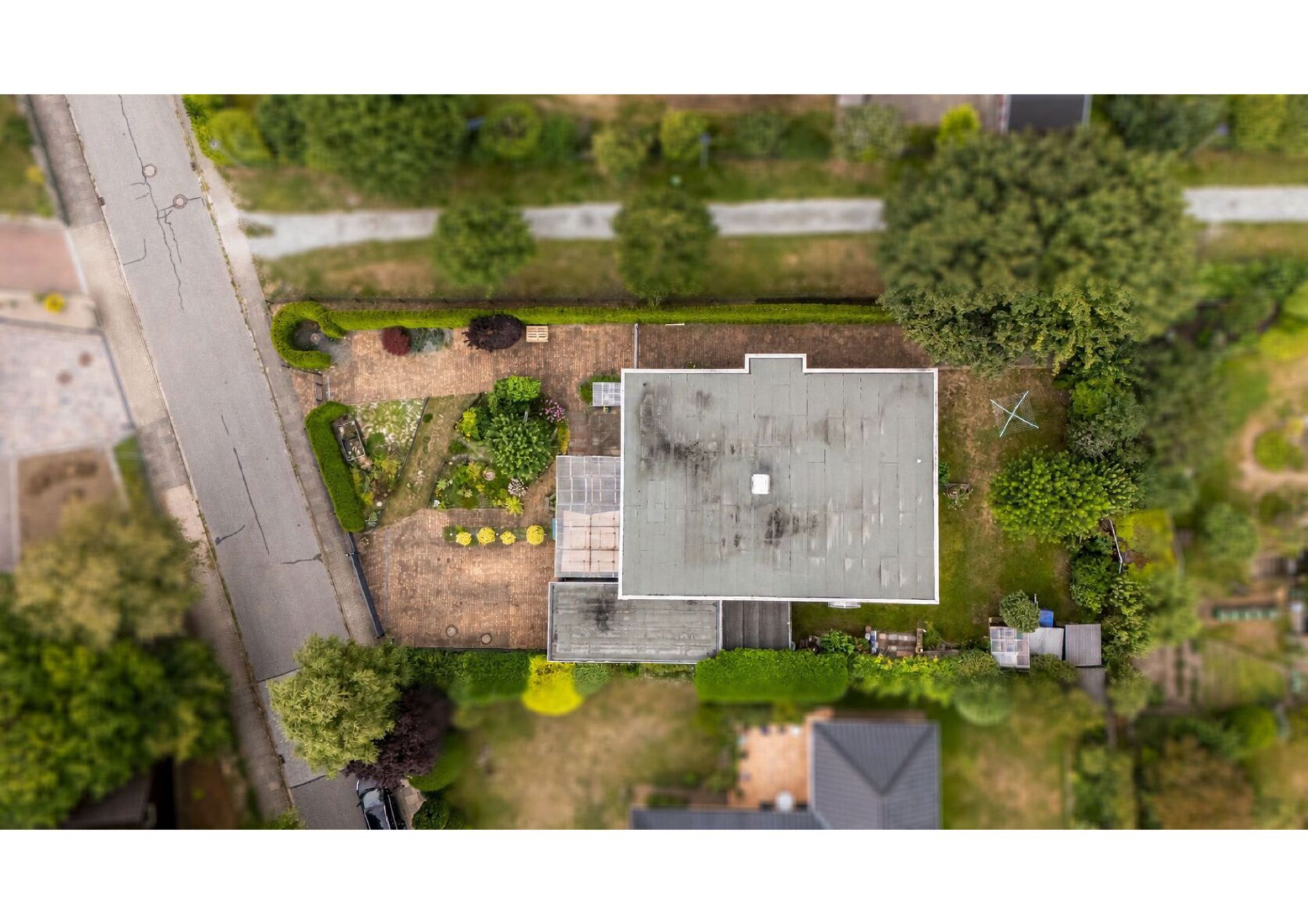 Luftaufnahme eines Hauses mit Garten, Terrasse und umliegender Straße.