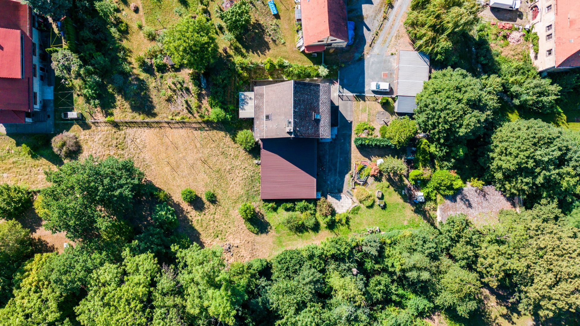 Luftaufnahme eines Wohnhauses mit Garten, Bäumen und umgebenden Grundstücken.