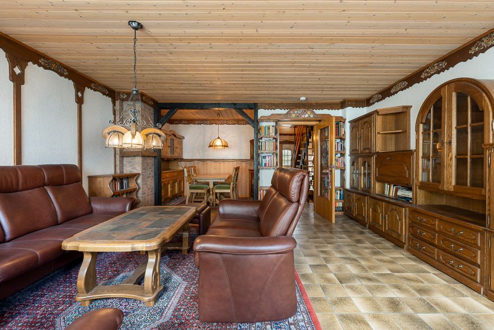 Wohnzimmer mit braunen Ledermöbeln, Holzmöbeln und Teppich, angrenzendem Essbereich.