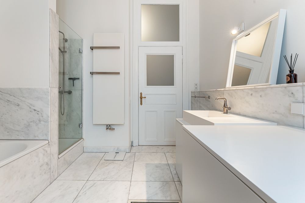 Helles Badezimmer mit Doppelwaschbecken, Dusche, Badewanne und großem Spiegel.