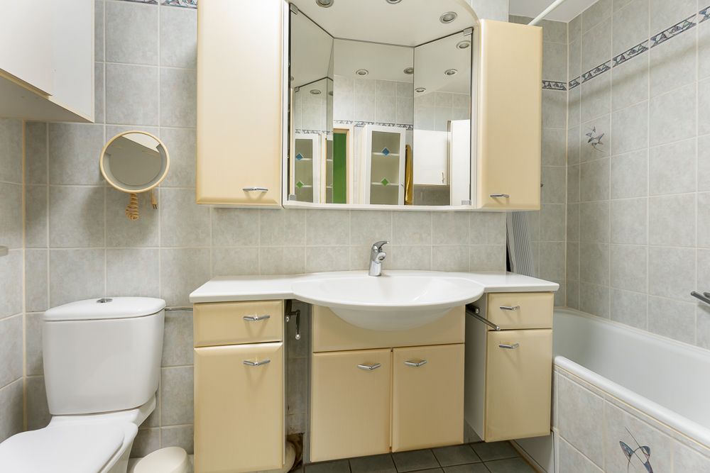 Helles Badezimmer mit Waschbecken, Spiegelschrank, Toilette und Badewanne.