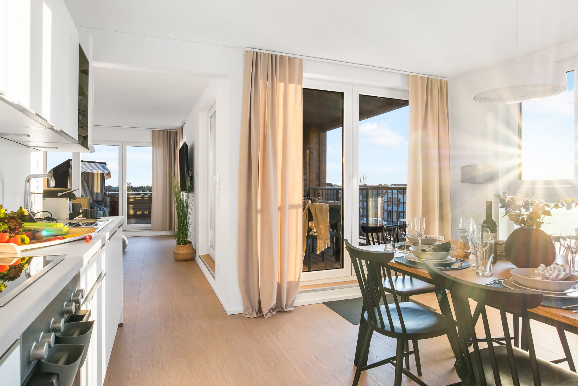 Helle Küche und Essbereich mit gedecktem Tisch, großem Fenster und Zugang zum Balkon.