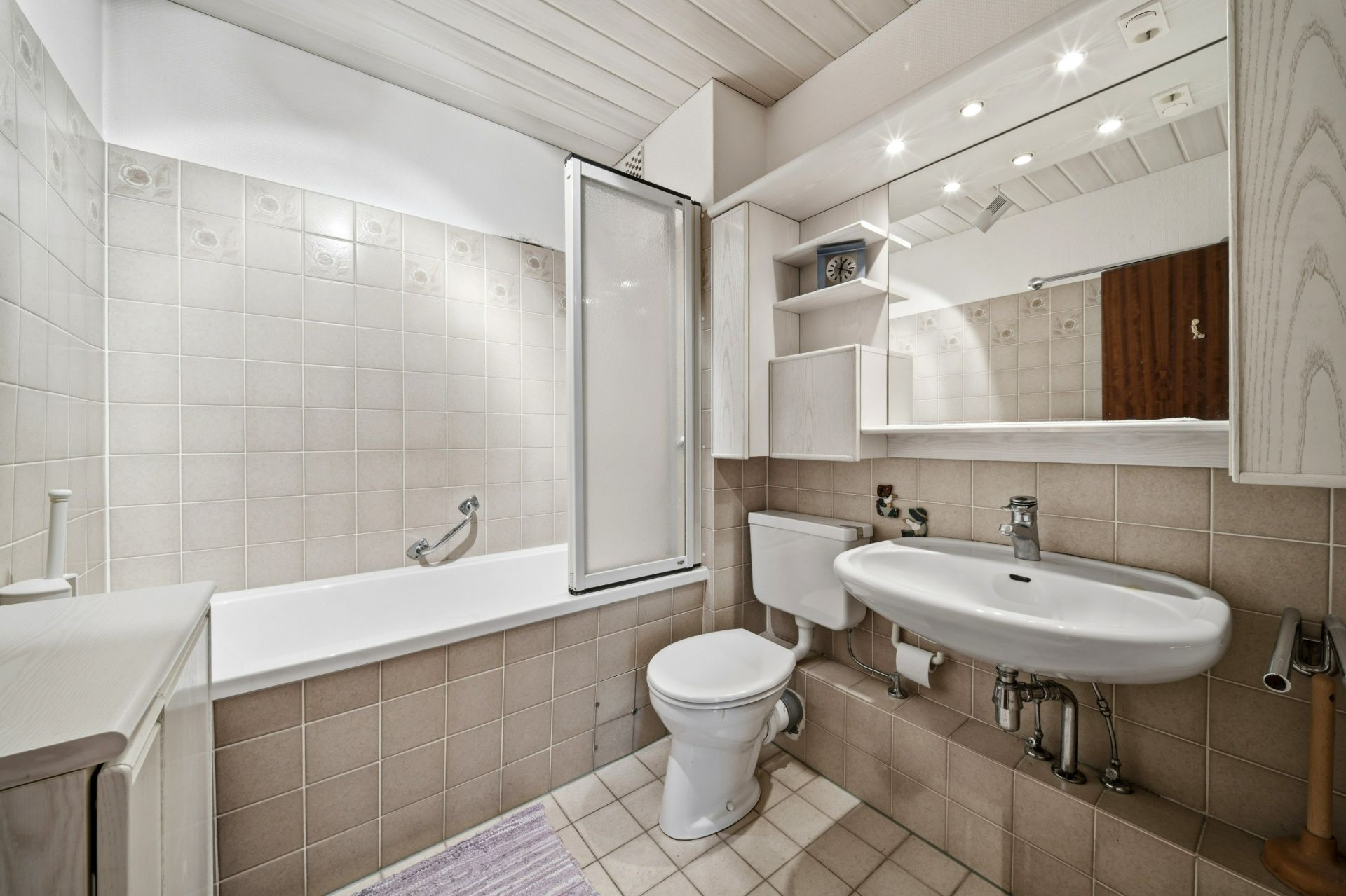 Helles Badezimmer mit Badewanne, WC, Waschbecken und großem Spiegel.