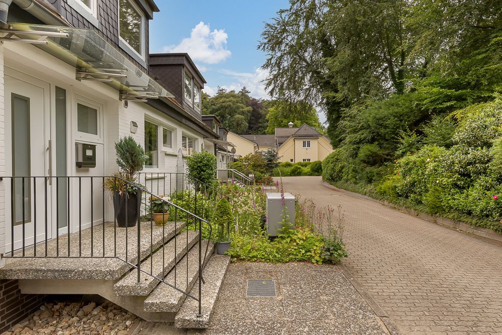 Eingang zu einem Reihenhaus mit kleinen Pflanzen neben den Stufen und einer ruhigen Straße davor.