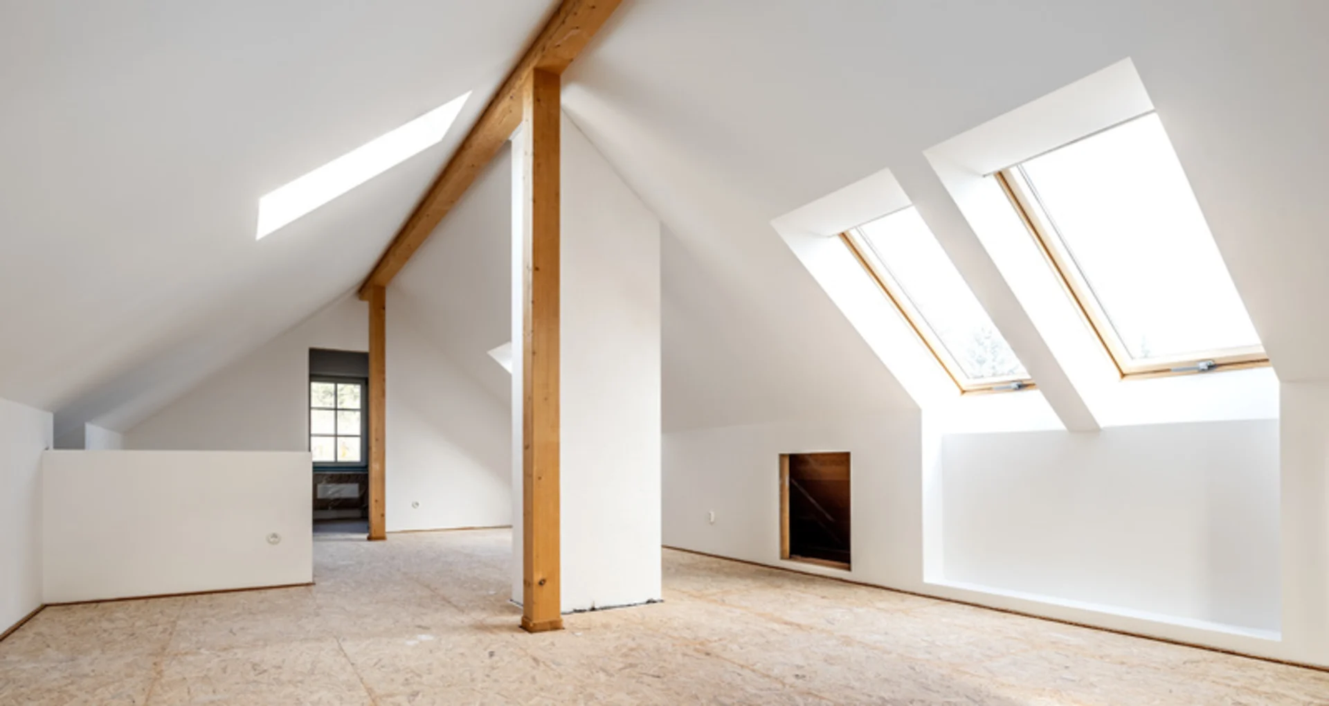 Heller Dachbodenraum mit Holzsäulen und großen schrägen Dachfenstern.