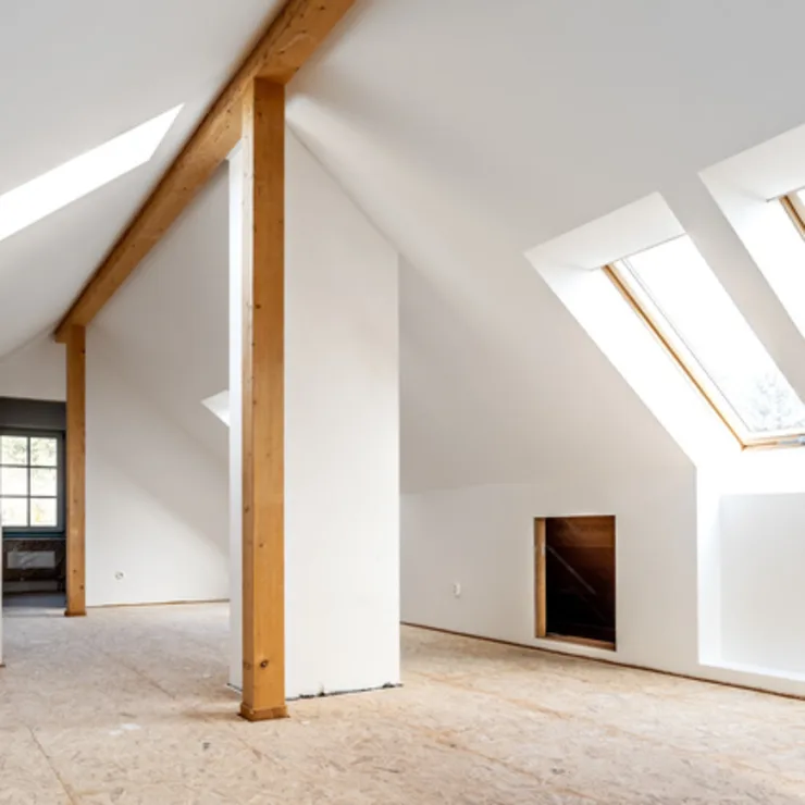 Heller Dachbodenraum mit Holzsäulen und großen schrägen Dachfenstern.