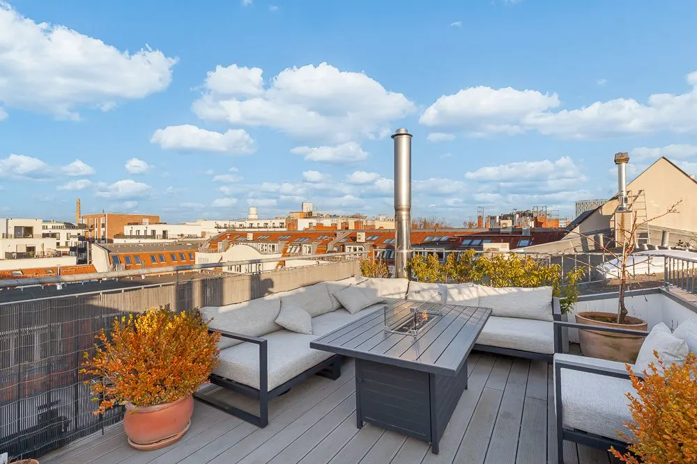 Dachterrasse mit Sitzgruppe, Tisch, Pflanzen in Töpfen und Blick über die Stadt.