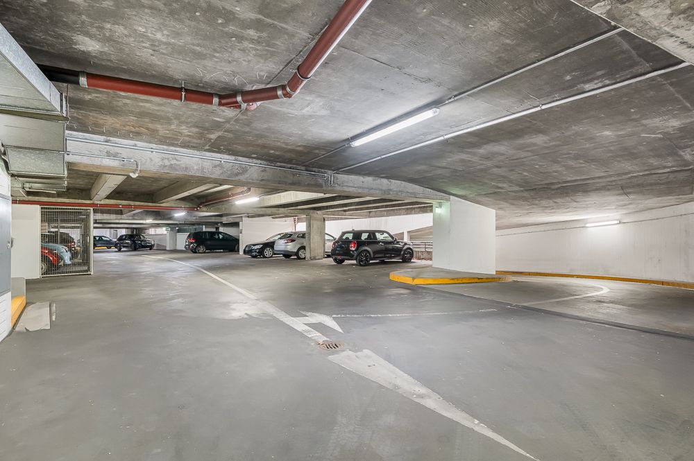 Helle Tiefgarage mit mehreren parkenden Autos und Betonwänden.