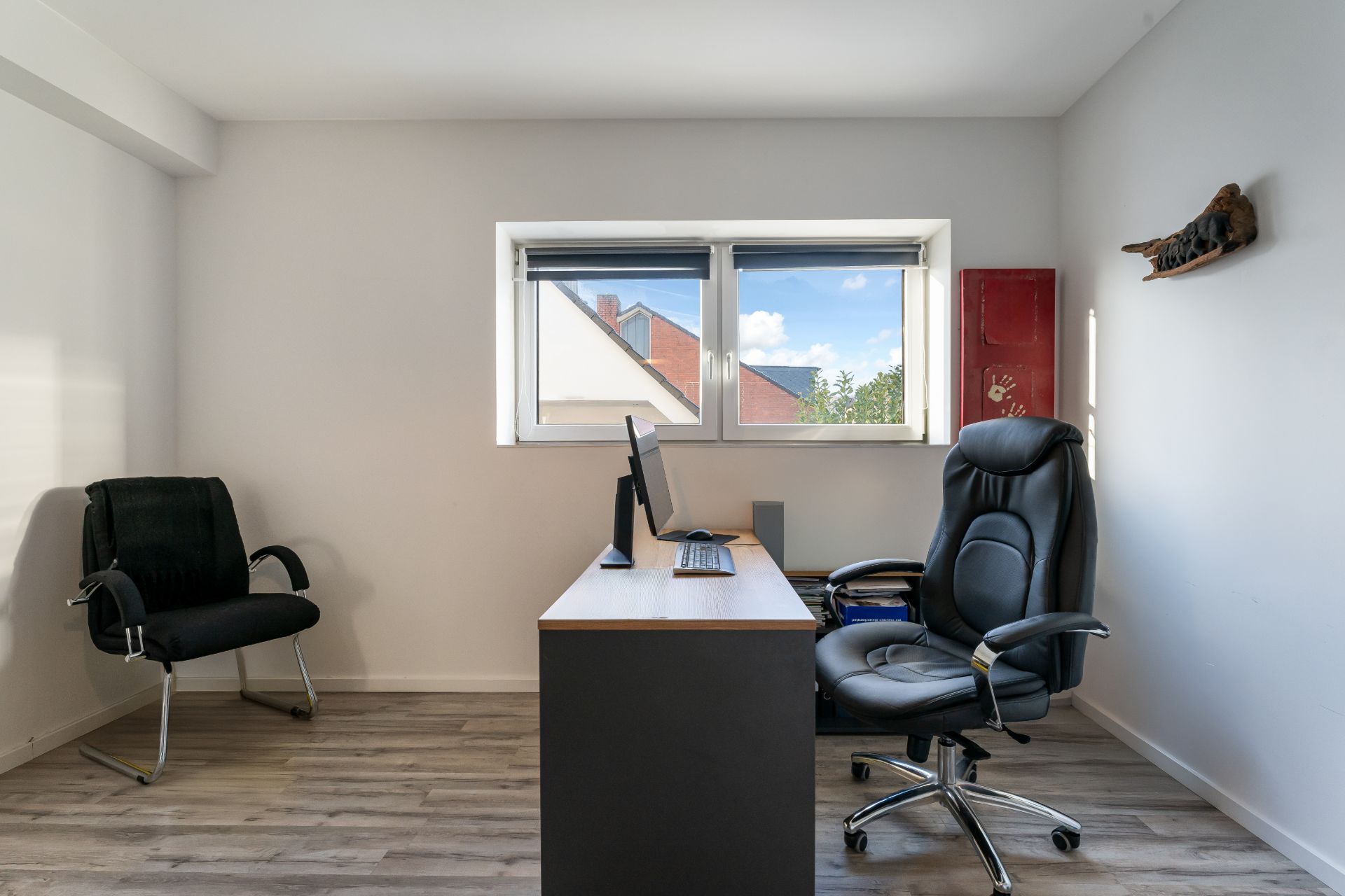 Helles Arbeitszimmer mit Schreibtisch, zwei Stühlen und Fenster mit Blick nach draußen.