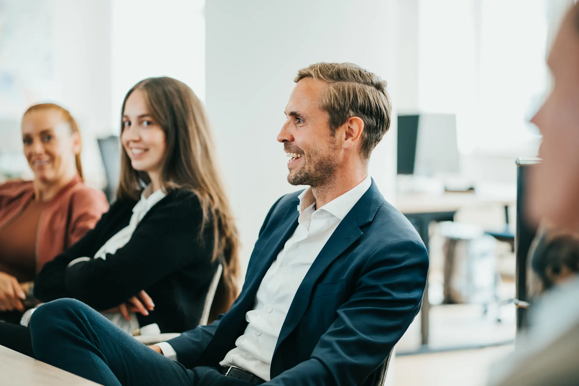 Mehrere Menschen sitzen und lächeln in einem modernen Büro.
