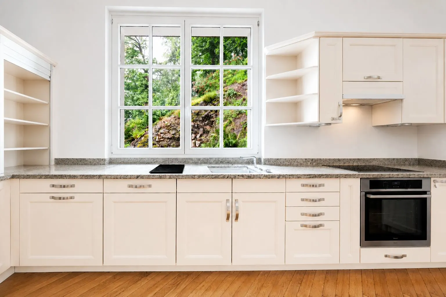 Helle Einbauküche mit weißen Schränken, Herd, Backofen und großem Fenster mit Blick ins Grüne.