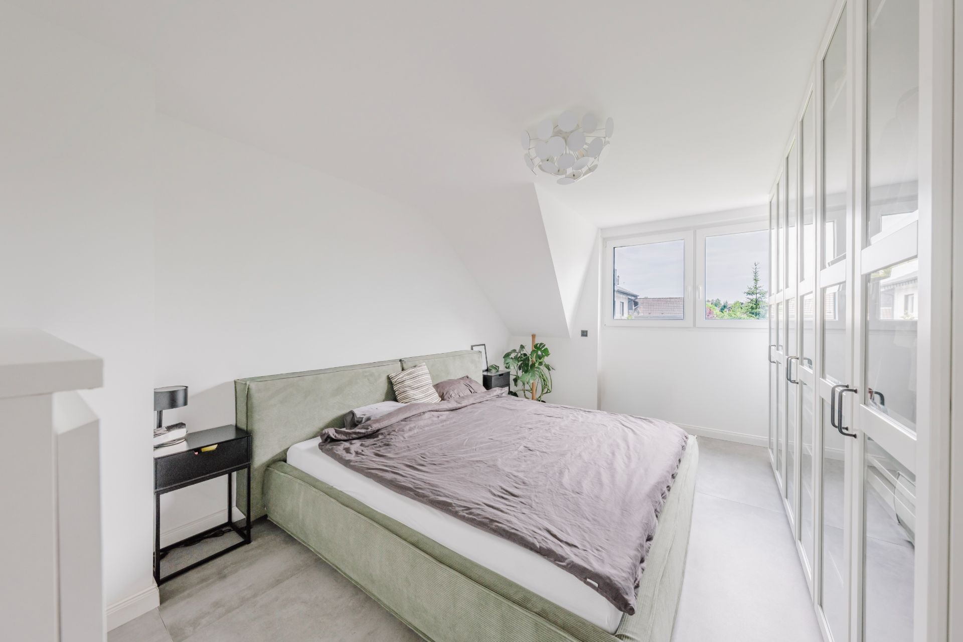 Helles Schlafzimmer mit Doppelbett, Nachttisch, Kleiderschrank und zwei Fenstern.