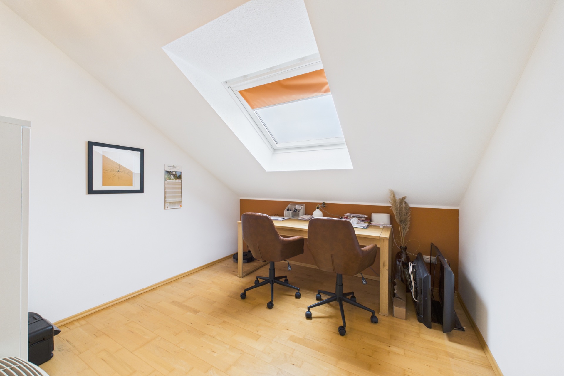 Helles Arbeitszimmer mit zwei Stühlen, Schreibtisch und Dachfenster.