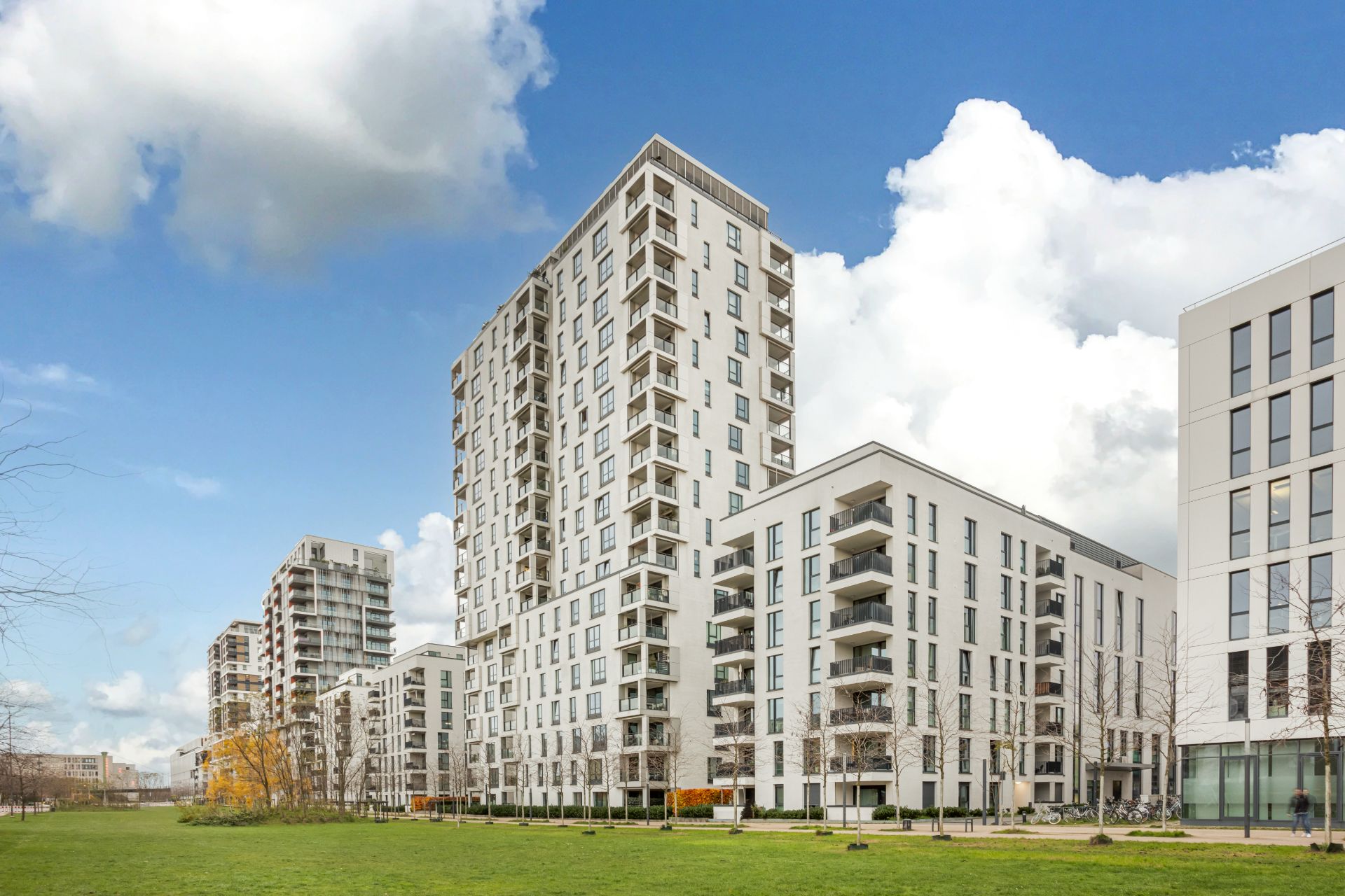 Mehrere moderne Wohngebäude mit Balkonen und großen Fenstern, davor eine Rasenfläche.