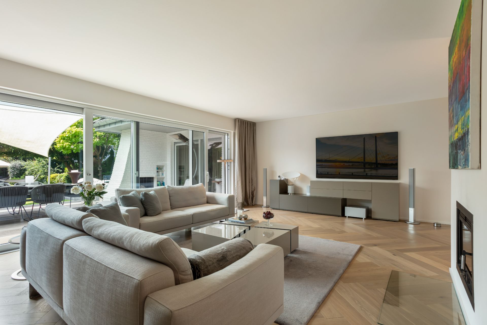 Helles Wohnzimmer mit zwei Sofas, Couchtisch, großem Fernseher und Zugang zur Terrasse.