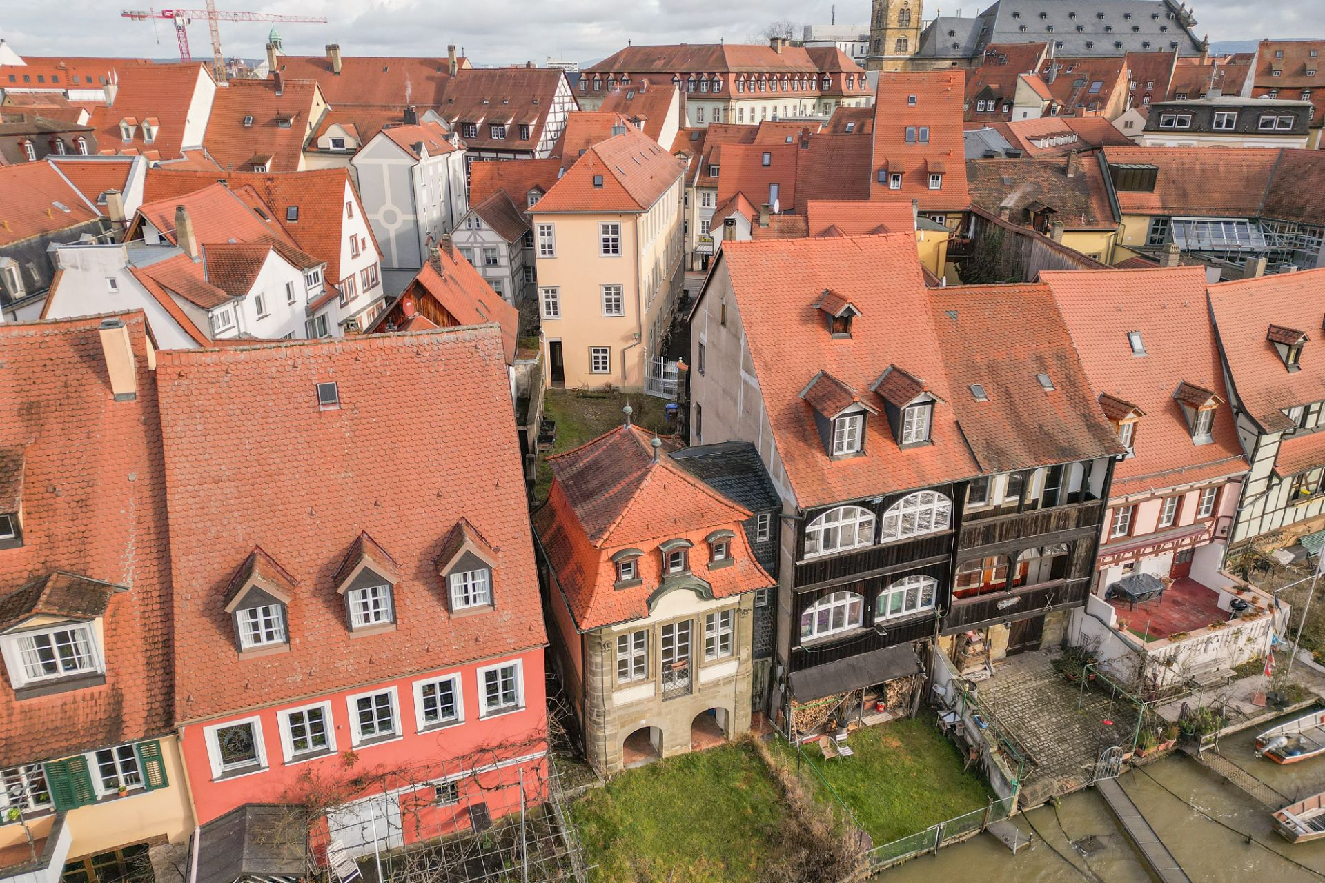 Luftaufnahme von Wohnhäusern mit roten Dächern und Fachwerk, an einem Fluss gelegen.