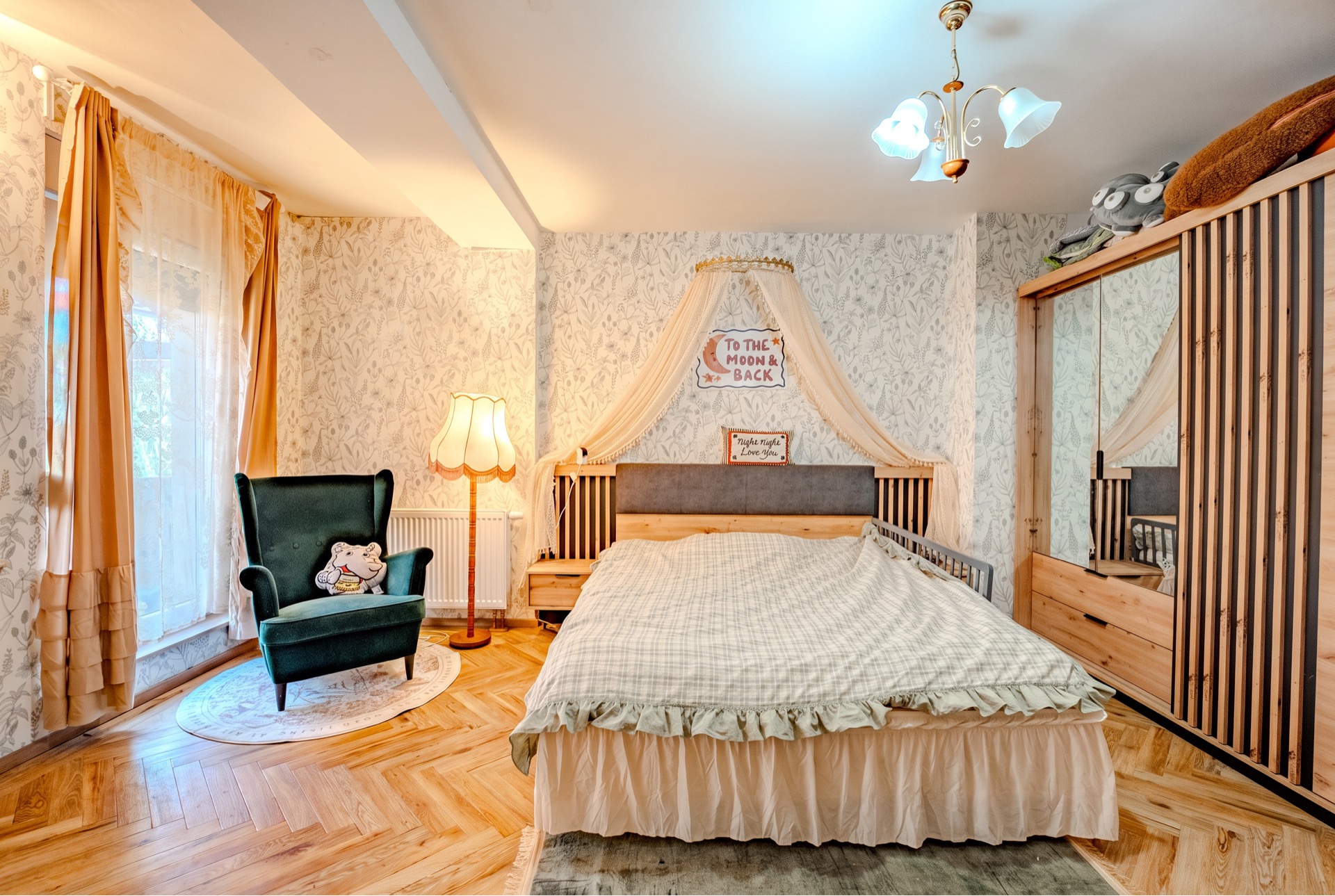 Gemütliches Schlafzimmer mit großem Bett, grünem Sessel, Stehlampe und Holzkleiderschrank.