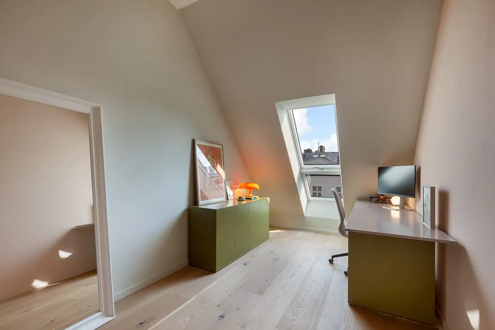 Helles Arbeitszimmer mit Schreibtisch, Stuhl und Dachfenster.