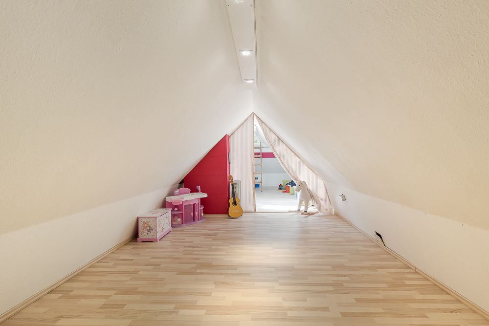 Heller Dachbodenraum mit Spielzeug, Gitarre und Kindermöbeln, Laminiertboden.