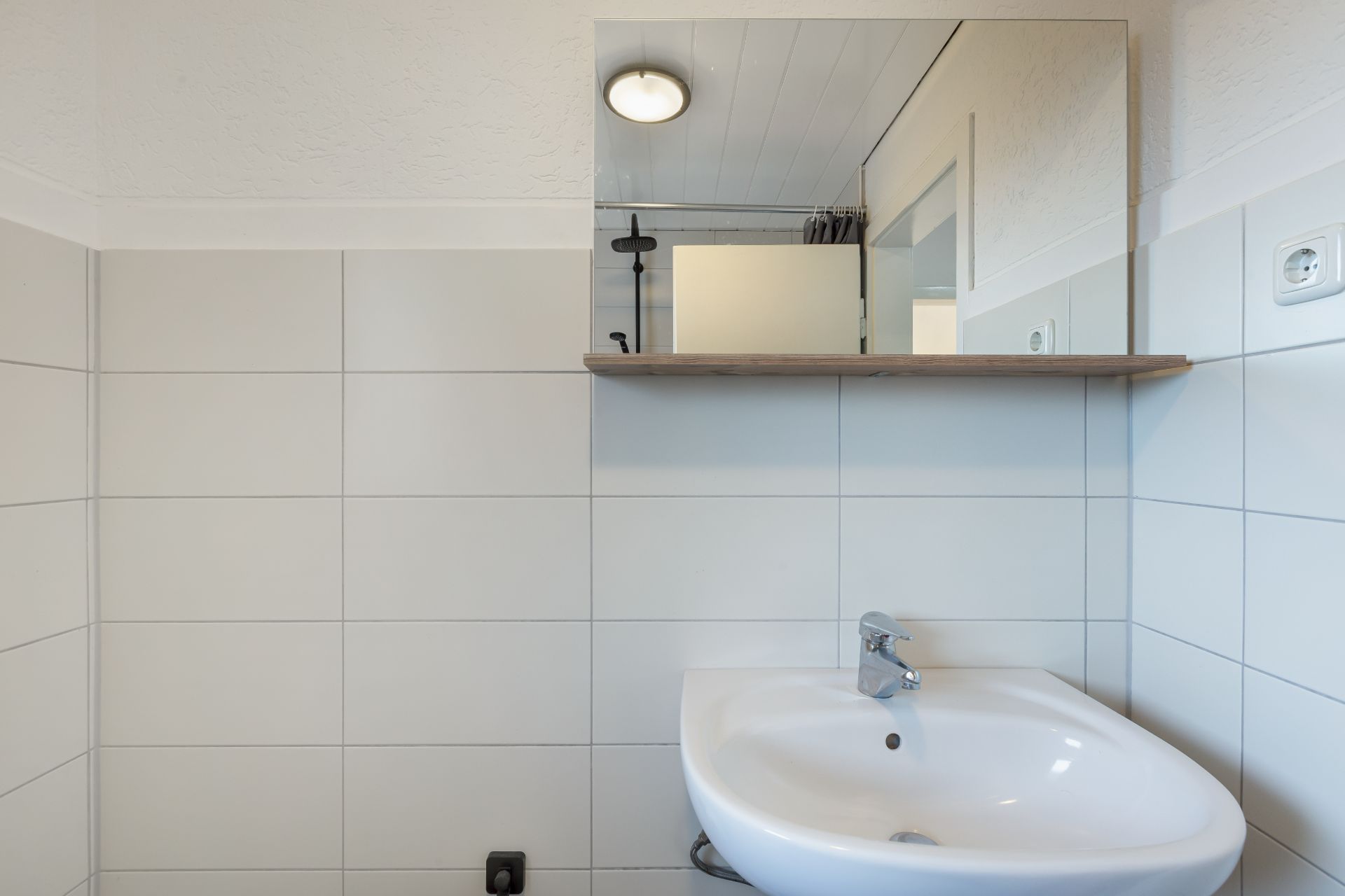 Waschbecken mit Spiegel und Fliesenwand in einem Badezimmer.