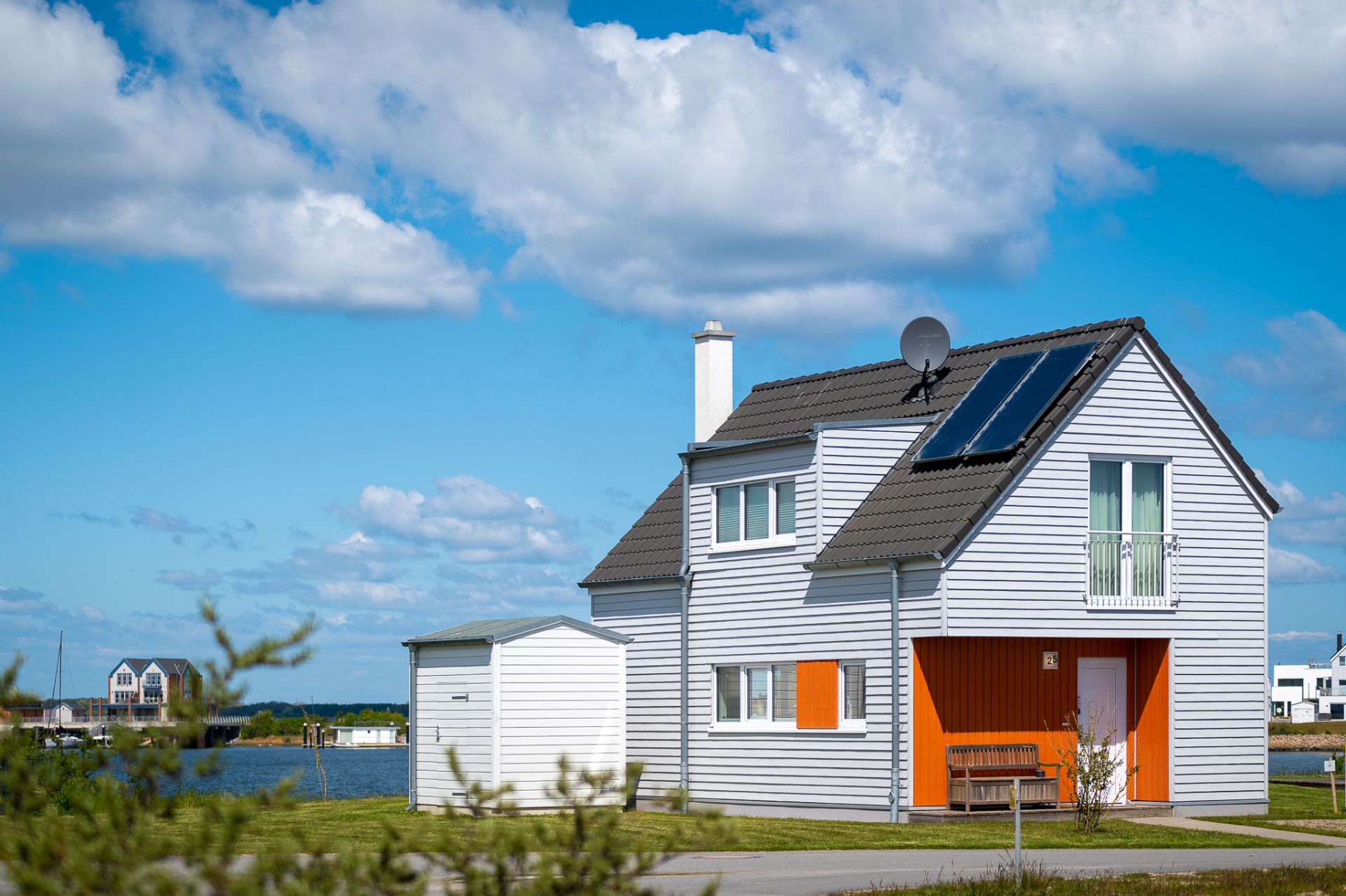 Modernes Einfamilienhaus mit Solarpanelen und Nebengebäude an einem sonnigen Tag.