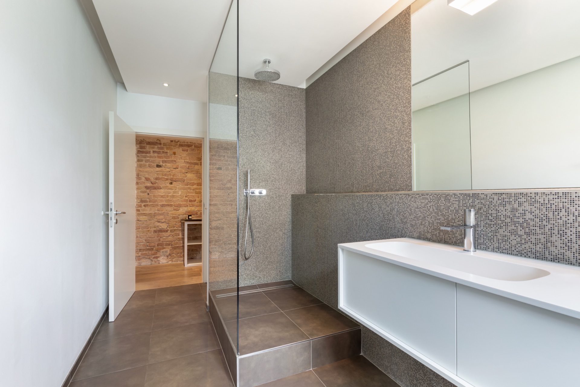 Modernes Badezimmer mit begehbarer Dusche, Waschbecken und großem Spiegel.